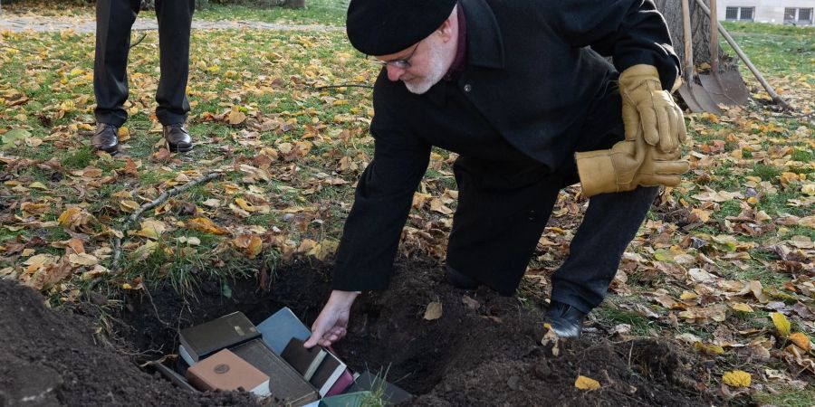 Der ehemalige Pastor Harald Storz legt an der St.-Albani-Kirche in Göttingen alte Bibeln, die nicht mehr gebraucht werden, in ein Grab.
