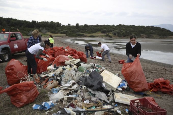Helfende sammeln Abfall an einem Strand in Griechenland ein. Meer