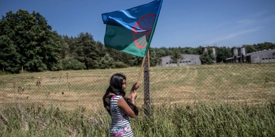 Eine Frau trägt eine Roma-Fahne während einer internationalen Gedenkveranstaltung zum Völkermord an den Roma vor einer Schweinefarm im tschechischen Lety. Der Betrieb steht auf dem Gelände eines ehemaligen Konzentrationslagers für Roma. (Archivbild)
