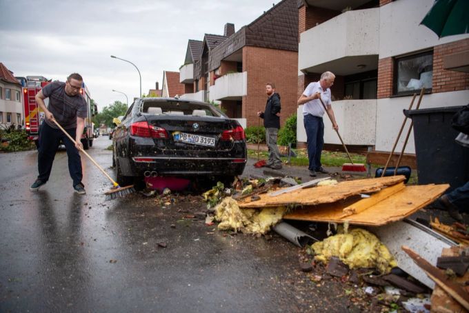 20.05.2022, Nordrhein-Westfalen, Paderborn: Leute fegen Trümmer von der Straße. Ein Unwetter hat auch in Paderborn große Schäden angerichtet. Paderborn