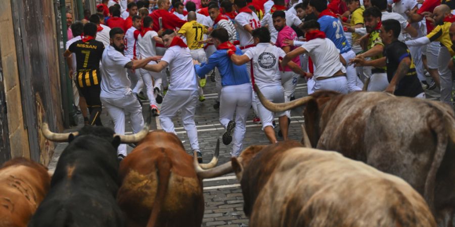 ARCHIV - Teilnehmer treiben die Stiere der Victoriano del RÌo CortÈs Ranch am vierten Tag der SanfermÌn-Festlichkeiten durch die Innenstadt. Foto: Miguel Oses/AP/dpa (Archivbild)
