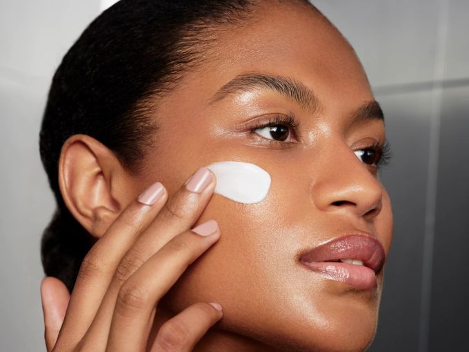 Der in der Skin Infusion enthaltene pflanzliche Vitamin-D-Aktivator verbessert nicht nur die Aufnahme von Vitamin D, sondern fördert auch die Strahlkraft der Haut, was einen gesunden, natürlichen Glow verleiht. Dunkelhäutiges Model cremt Gesicht ein mit Augustinus Bader