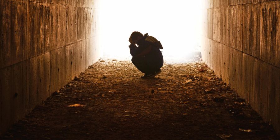 Mann sitzt verzweifelt im Tunnel.