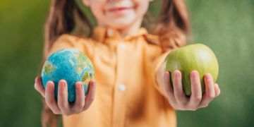 Mädchen Hände gestreckt rechts Apfel links Erdkugel