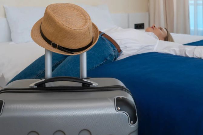 Hotelgast liegt auf dem Bett, Koffer, Hut