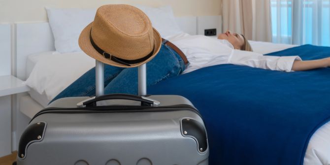 Hotelgast liegt auf dem Bett, Koffer, Hut