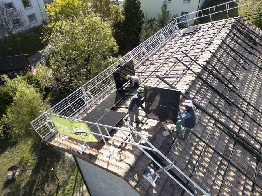Solarinstallateure der Greencover AG tragen ein Solarpanel auf das Dach eines Hauses in Pfäfers SG, am 6. November 2024.