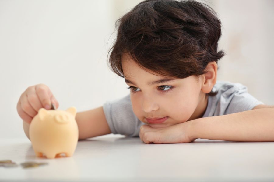 Junge wirft Geld in ein Sparschwein