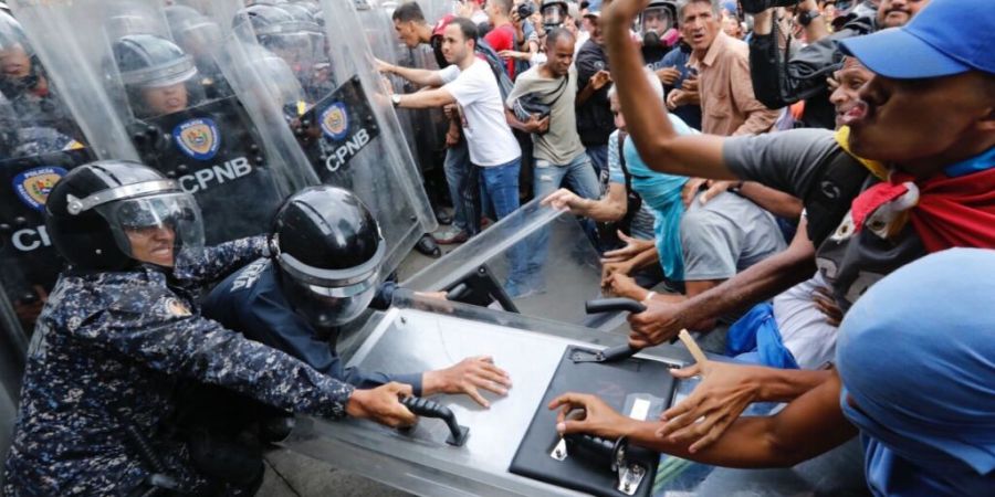 ARCHIV - Anhänger der Opposition ziehen an einem Schutzschild während eines Protests in Caracas (Archivbild). Foto: Ariana Cubillos/AP/dpa