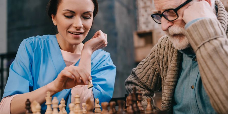 krankenschwester spielt mit altem mann schach