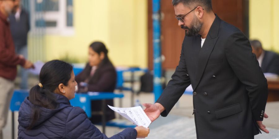 Balendra Shah (r), ehemaliger Bürgermeister der Stadt Kathmandu und Premierministerkandidat der Rastriya Swatantra Party, zeigt seinen Personalausweis, bevor er seine Stimme in einem W...
