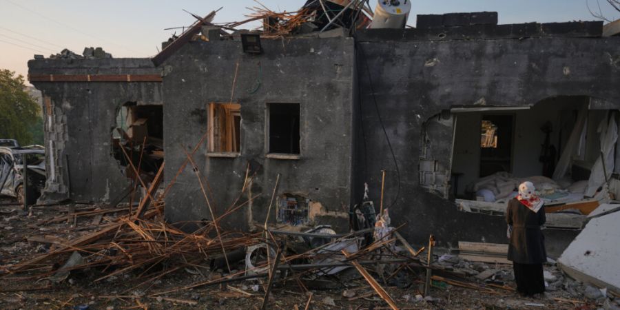 Eine Frau betrachtet ein durch einen iranischen Raketenangriff zerstörtes Haus. Foto: Ariel Schalit/AP/dpa