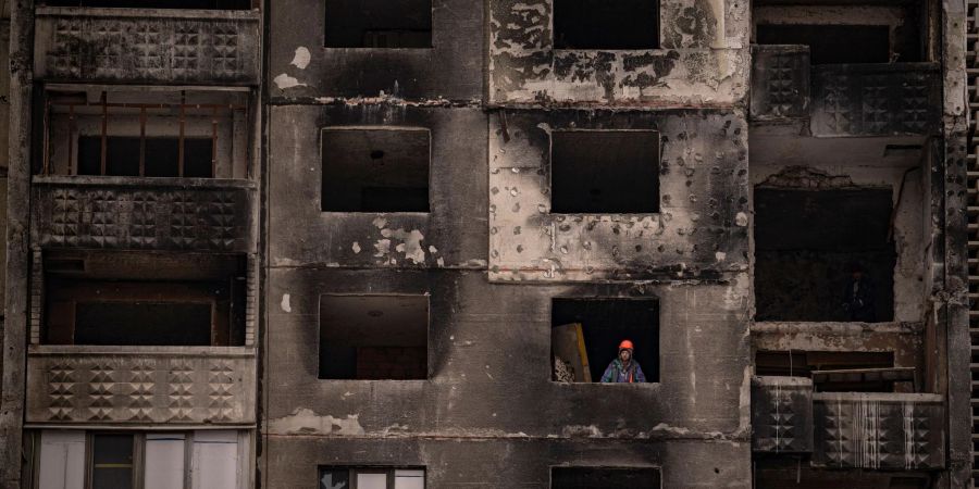 Ein Bauarbeiter steht am Fenster eines durch russischen Beschuss beschädigten Gebäudes in Charkiw.