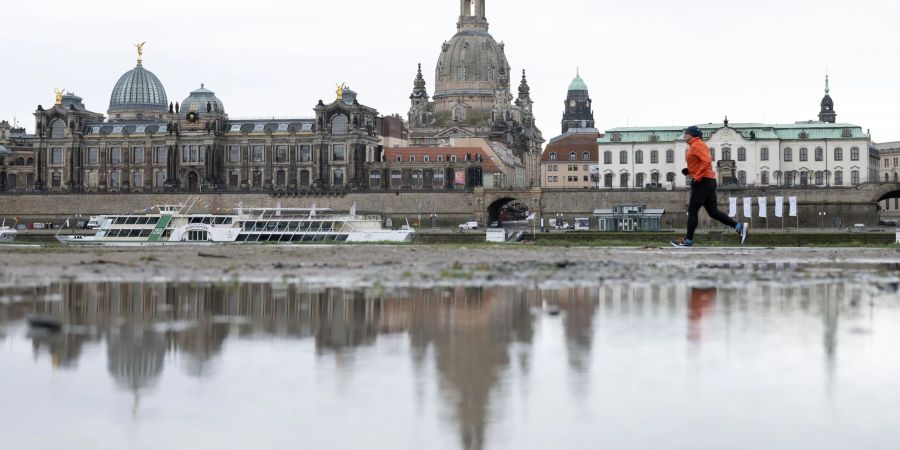 Ein Jogger am Ufer der Elbe vor der Kulisse Dresdens.
