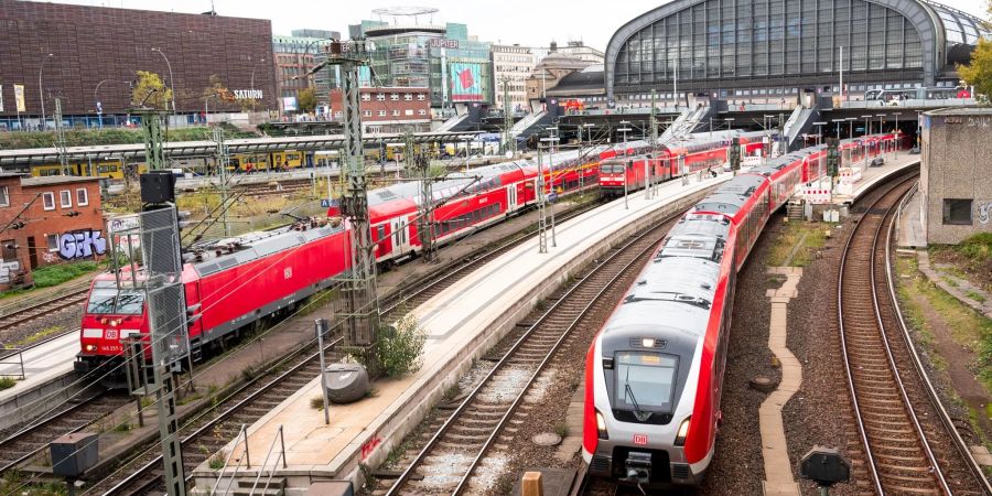 Eine S-Bahn fährt aus dem Hauptbahnhof in Hamburg aus. Daneben stehen zwei Regionalzüge der Deutschen Bahn.