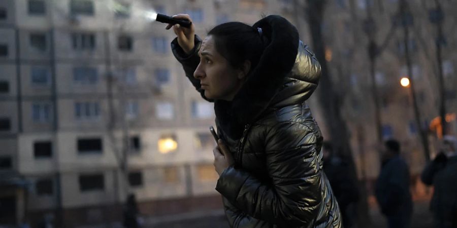 Nadiia Yaroshenko versucht ihre Katze mit einer Taschenlampe zu finden, die in einem beschädigten Gebäude in Dnipro eingeschlossen ist. Foto: Roman Hrytsyna/AP/dpa