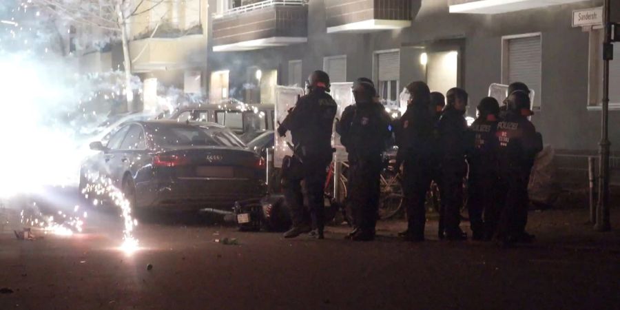 Polizeibeamte hinter explodierendem Feuerwerk in Berlin. Nach Angriffen auf Einsatzkräfte hat die Diskussion um Konsequenzen begonnen.