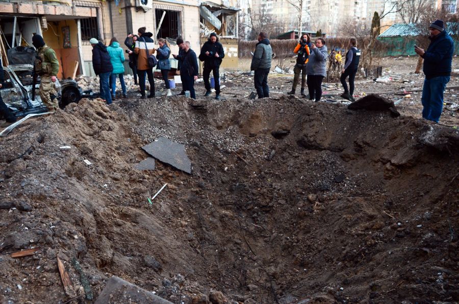 Gesamtansicht des Kraters, den eine Granate vor einem beschädigten Wohnhaus nach dem Beschuss eines Wohngebiets im Kiewer Stadtteil Swjatoschynski durch russische Truppen hinterlassen hat.