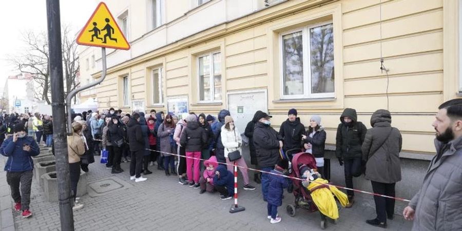 Aus der Ukraine geflüchtete Menschen stehen vor einer Meldestelle Schlange. Foto: Czarek Sokolowski/AP/dpa