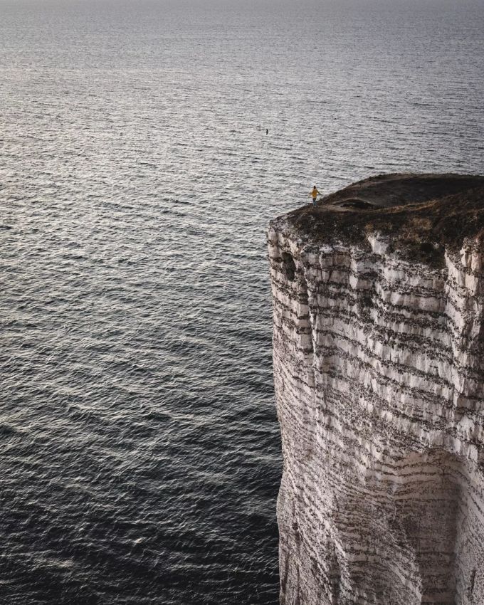 Eine Person steht auf den Klippen von Étretat in der Normandie. Étretat Klippen
