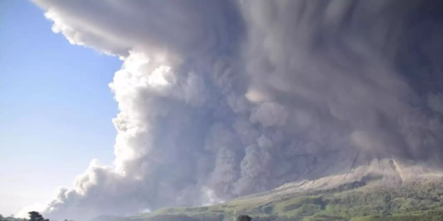 Menschen beobachten eine Eruption des Vulkans Sinabung. Foto: Uncredited/AP/dpa