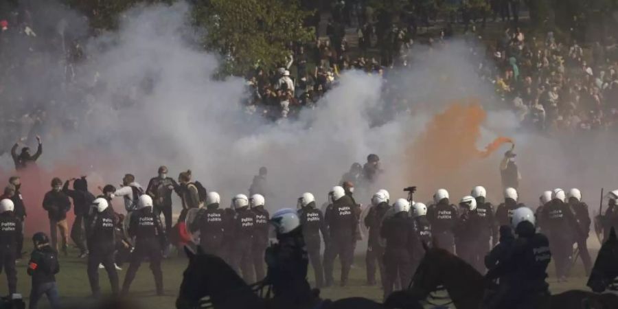 Polizisten setzen Tränengas gegen Demonstranten ein. Foto: Olivier Matthys/AP/dpa