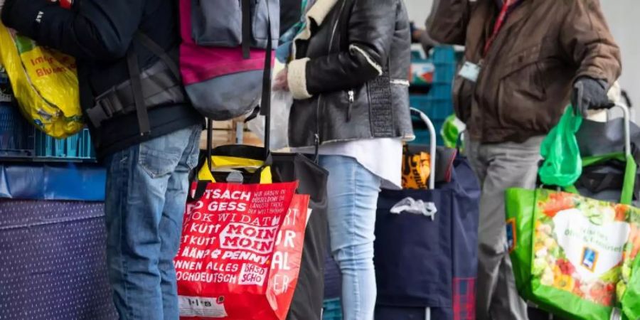 Gäste der Münchner Tafel stehen an der Ausgabestelle am Grossmarkt. Foto: Sven Hoppe/dpa