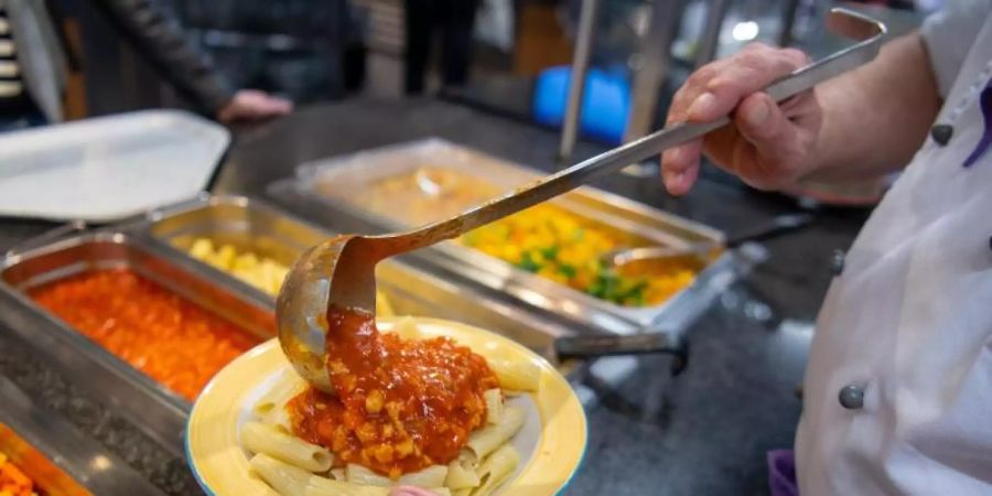 Ein Koch serviert in der veganen Mensa auf dem Campus der Technischen Universität in Berlin ein veganes Gericht. Foto: Monika Skolimowska/dpa-Zentralbild/dpa