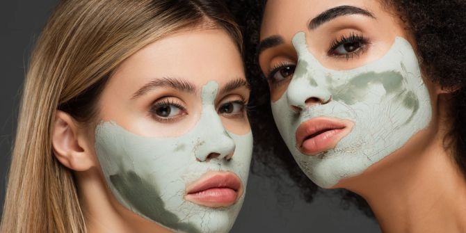 zwei multiethnische frauen tragen beauty-maske, grauer hintergrund