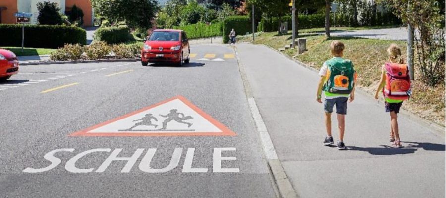 Bodenmarkierung «Achtung Schule» auf der Fahrbahn im Bereich der Schulanlage.