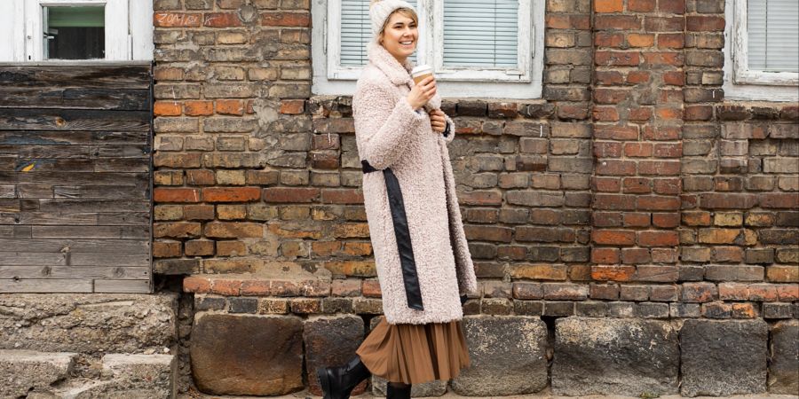 Streetstyle Frau in Kuschelmantel mit Boots auf der Strasse.