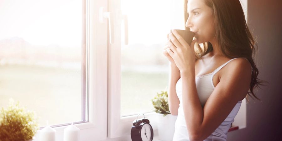 Frau steht am Fenster