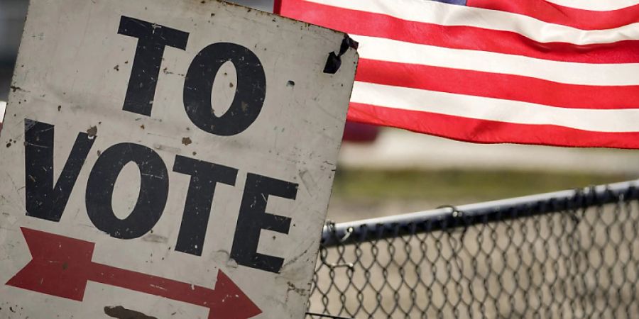 Ein Wahlschild und eine amerikanische Flagge sind vor einem Vorwahlbüro in Dearborn, Michigan zu sehen. Foto: Paul Sancya/AP/dpa