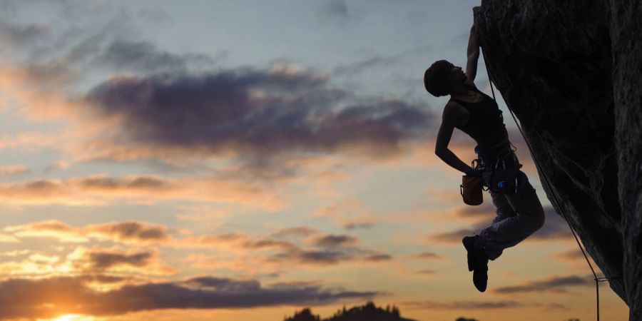 Frau klettert im Sonnenuntergang.