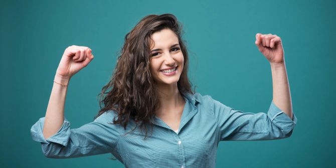 dunkelhaarige frau streckt optimistisch die arme nach oben