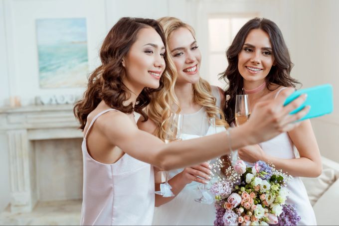 Selfies gehören bei Hochzeiten dazu - mitunter wird sogar eine Ecke dafür eingerichtet. Brautjungfern machen Selfies.