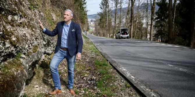 Mann begutachtet Hang an einer Strasse