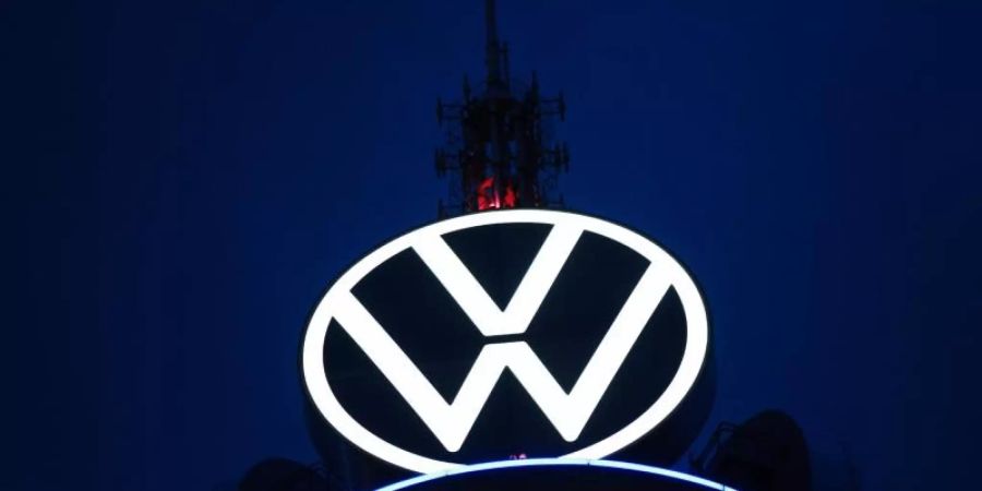 Das Volkswagen Logo leuchtet auf dem VW-Tower vor dunklem Himmel. Foto: Ole Spata/dpa