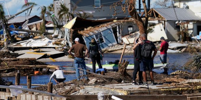 Menschen betrachten von einer zerstörten Brücke in Matlacha im US-Bundesstaat Florida aus die Schäden nach dem Hurrikan Ian. (Gerald Herbert/AP/dpa) ian