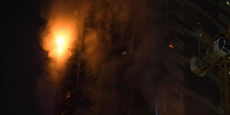 Ein Feuer brennt an der Seite des Hochhauses in Schardscha. Foto: Jon Gambrell/AP/dpa