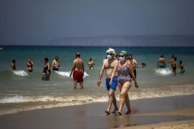 Ein Paar mit Gesichtsmasken geht an einem Strand in Cádiz am Ufer entlang. Virus Outbreak Spain