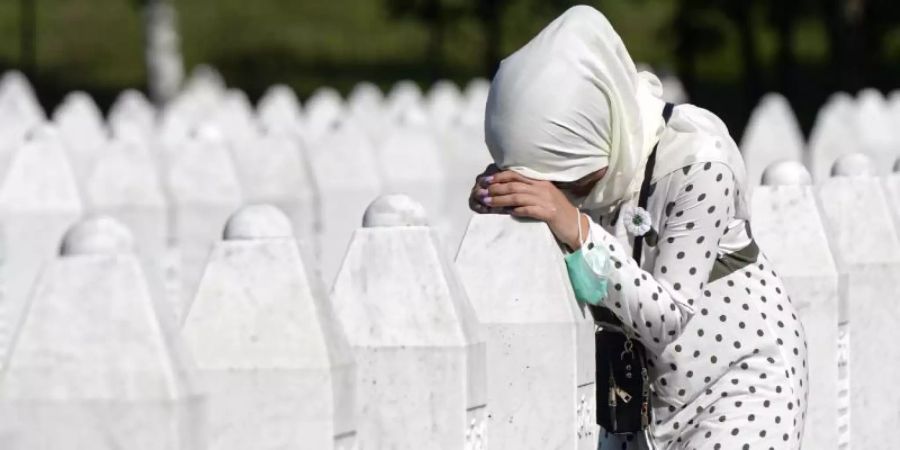 Eine Frau trauert auf dem Friedhof der Gedenkstätte Potocari in der Nähe von Srebrenica an einem Grab. Foto: Kemal Softic/AP/dpa