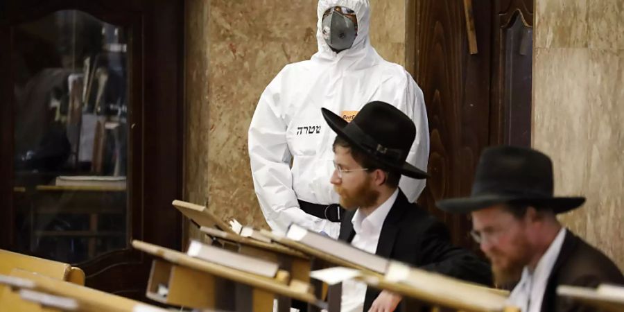 Ein israelischer Polizeibeamter betrachtet zwei orthodoxe Juden in einer Synagoge in Tel Aviv. (Archivbild)