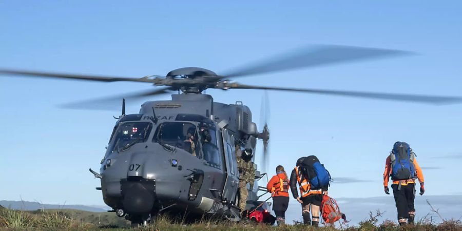 HANDOUT - Rettungshelfer gehen während eines Einsatzen an Board eines Hubschraubers. Zwei in der Wildnis Neuseelands vermisste Wanderer sind nach 18 Tagen lebend gefunden worden. Eine Helikopterbesatzung entdeckte am Mittwoch Rauchschwaden eines Feuers, das die beiden 23-jährigen Dion Reynolds und Jessica O'Connor in ihrem selbsterrichteten Notlager im Busch angezündet hatten. Foto: Cpl Naomi James/New Zealand Defence Force/AP/dpa - ACHTUNG: Nur zur redaktionellen Verwendung im Zusammenhang mit der aktuellen Berichterstattung und nur mit vollständiger Nennung des vorstehenden Credits