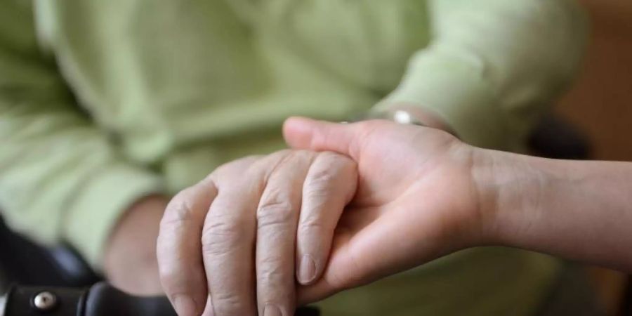 Eine junge Frau hält die Hände eines alten Mannes. Foto: Jens Kalaene