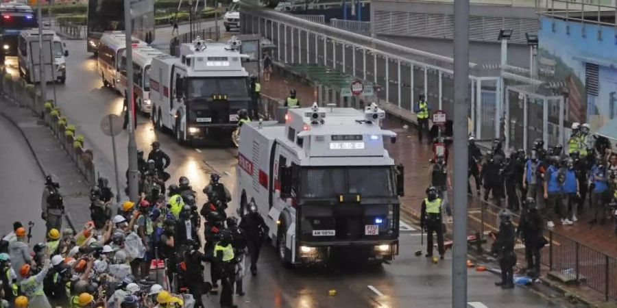 Polizisten stehen neben einem Wasserwerfer. Foto: Kin Cheung/AP