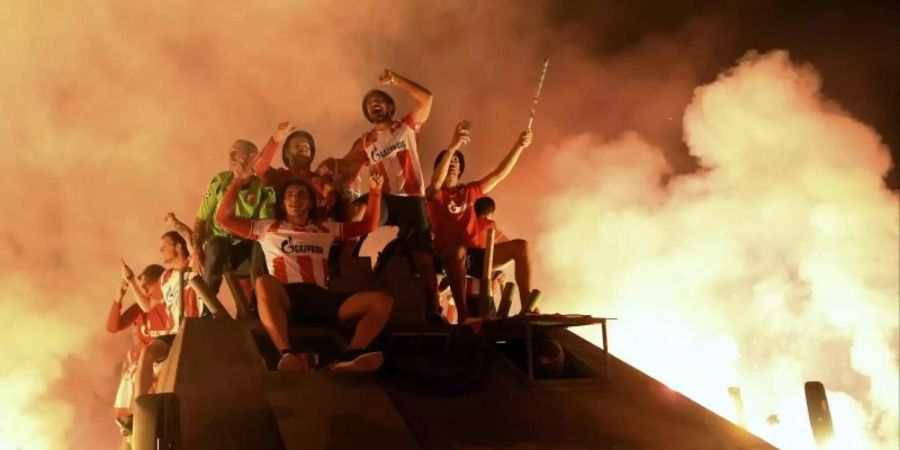 Spieler und Fans von Roter Stern Belgrad feiern mit Fackeln auf einem offenen Panzerfahrzeug den Einzug in die Gruppenphase der Champions League. Foto: AP