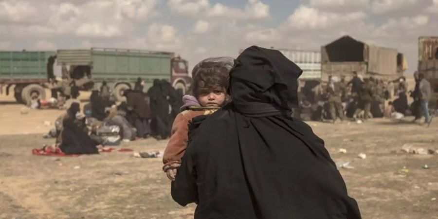 Eine Frau trägt ihr Kind durch ein Lager im syrischen Baghus, in dem Angehörige von IS-Kämpfern untergebracht sind. Foto: Gabriel Chaim/AP/Archiv