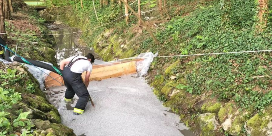 Ein Feuerwehrmann errichtet eine Sperre in einem Bach nachdem bei Schweizersholz TG rund 50 Kubikmeter Gülle ausgelaufen sind.