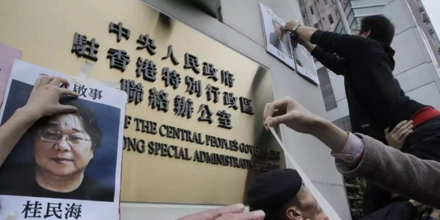 Demonstranten versuchen bei einer Kundgebung ein Foto des Hongkonger Buchhändlers Gui Minhai aus Protest gegen seine Verhaftung am Regierungssitz zu befestigen. Foto: Vincent Yu/AP/dpa